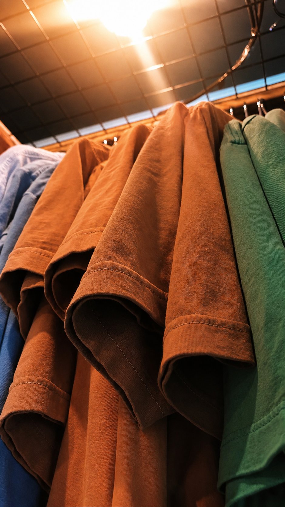 Camisetas DMATTEX dobradas, em diferentes cores